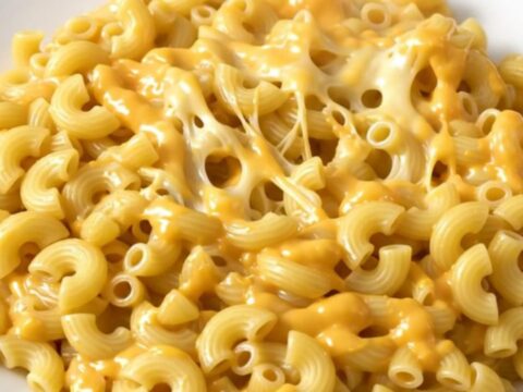 A steaming, creamy bowl of four cheese macaroni and cheese served in a white bowl.