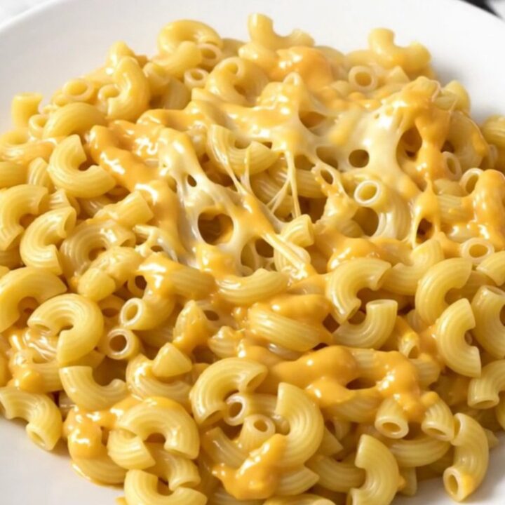 A steaming, creamy bowl of four cheese macaroni and cheese served in a white bowl.
