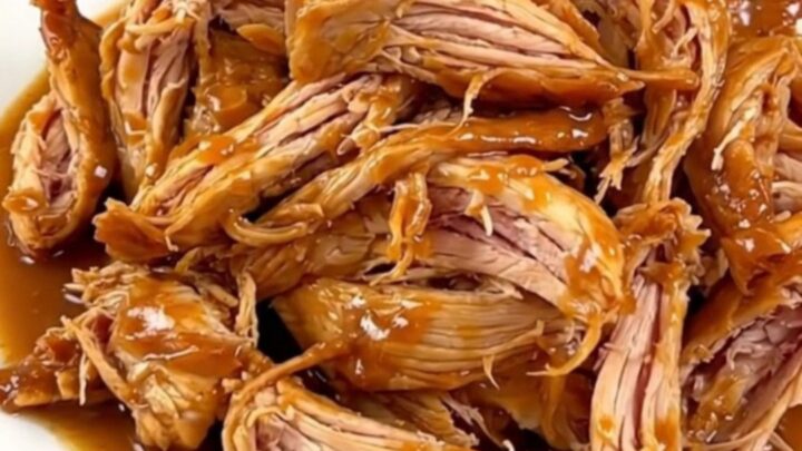 A whole chicken cooked in a slow cooker with colorful peppers and onions, ready to be shredded.