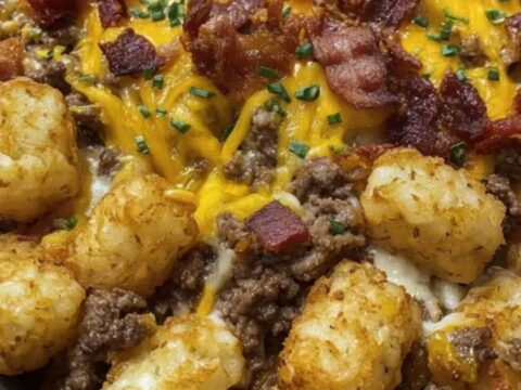 A portion of bacon cheeseburger tater tot casserole being lifted with a spatula, showing melted cheese pull