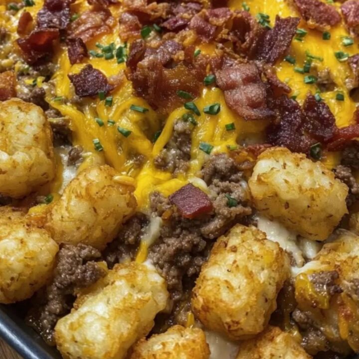 A portion of bacon cheeseburger tater tot casserole being lifted with a spatula, showing melted cheese pull