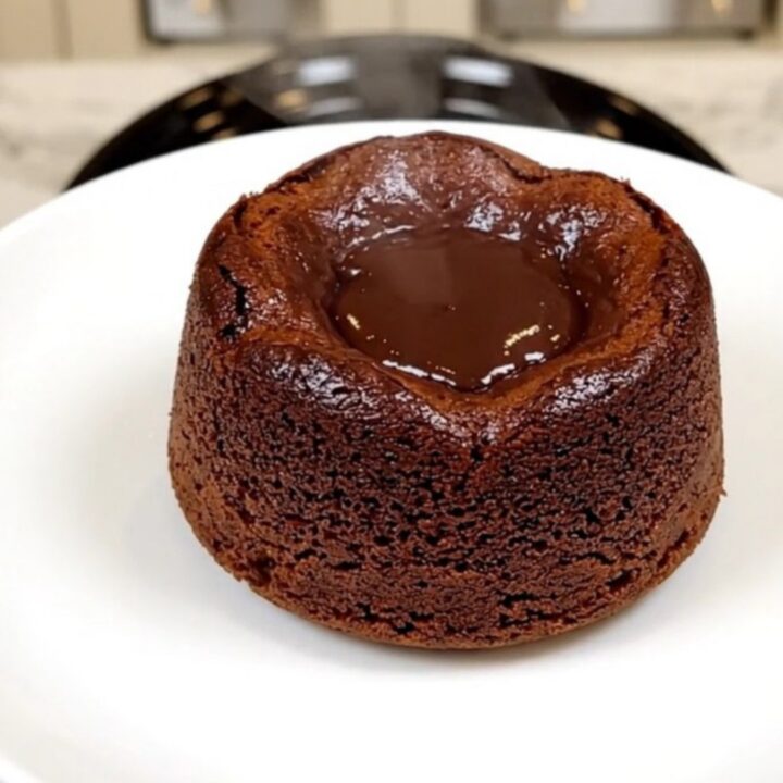 A top-down view of a black slow cooker filled with layers of chocolate cake mix, chips, and pudding before cooking.