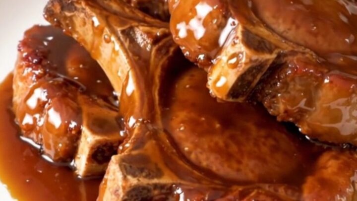 Close-up of glossy honey garlic pork chops on a white plate with visible glaze and steam.