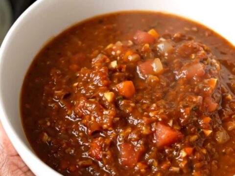 A white bowl filled with steaming black bean and turkey chili sitting on a bright kitchen counter.