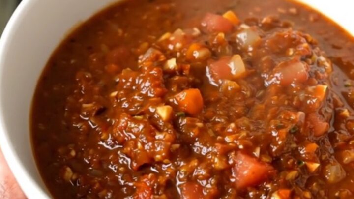 A white bowl filled with steaming black bean and turkey chili sitting on a bright kitchen counter.