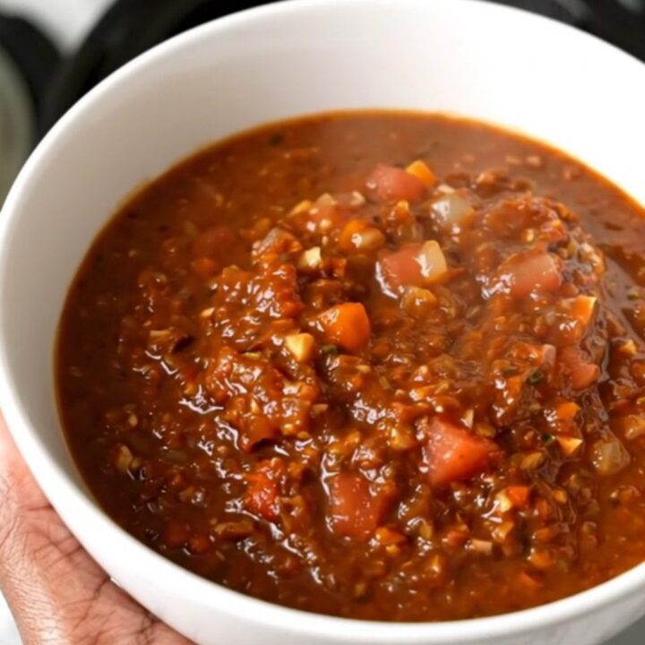 A white bowl filled with steaming black bean and turkey chili sitting on a bright kitchen counter.
