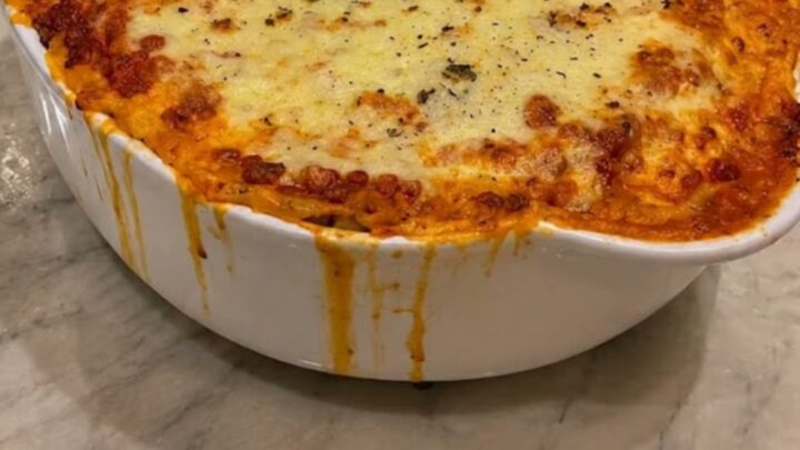 A deep, steaming slice of cheesy baked lasagna being lifted with a spatula, showing thick melted mozzarella cheese pulls.