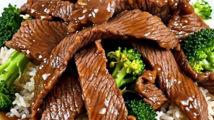 A white round plate featuring tender beef slices and bright green broccoli florets served over fluffy white rice.