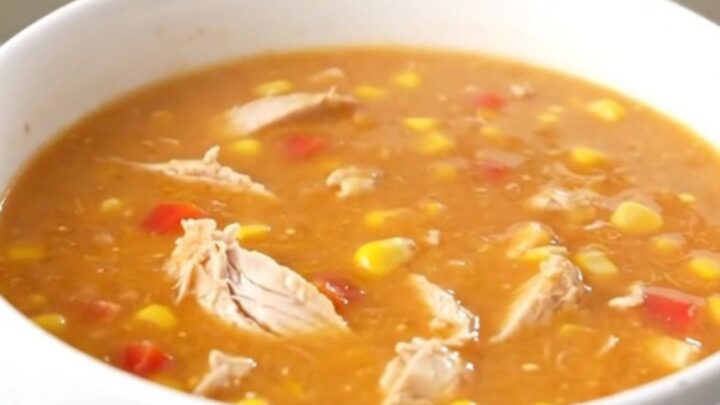 A steaming bowl of creamy buffalo chicken chowder with visible shredded chicken and corn.