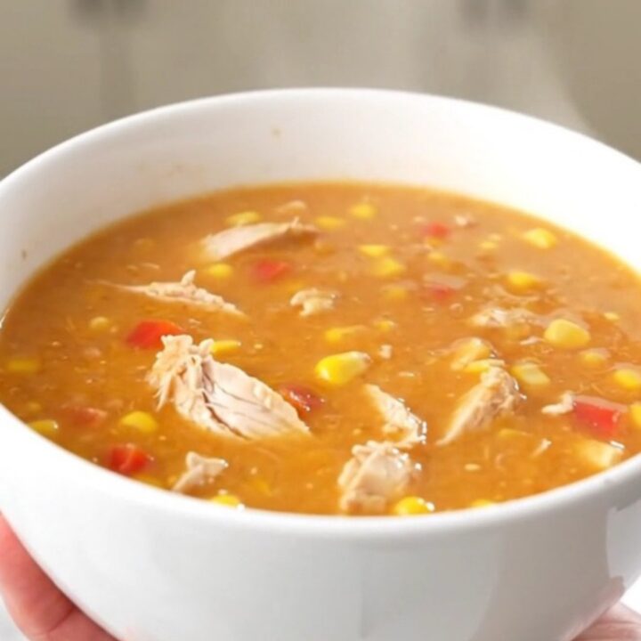 A steaming bowl of creamy buffalo chicken chowder with visible shredded chicken and corn.