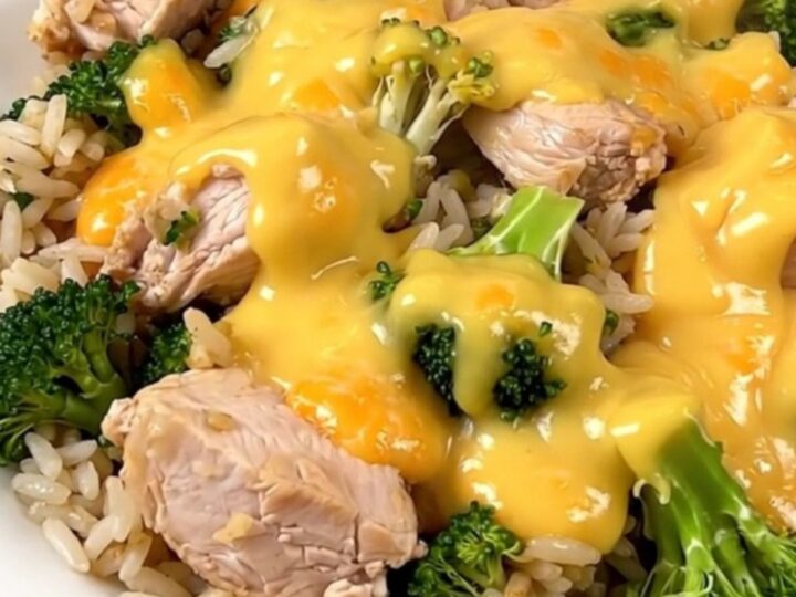 A slow cooker filled with chicken, broccoli, and a creamy cheddar sauce on a white speckled quartz countertop.