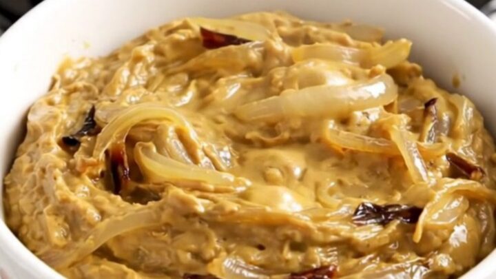 A bowl of warm, creamy French onion dip with caramelized onions, ready to be served with crackers.