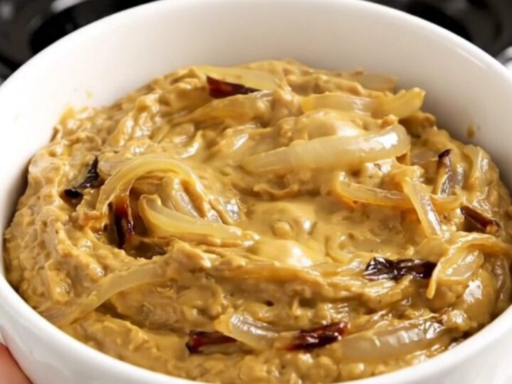 A bowl of warm, creamy French onion dip with caramelized onions, ready to be served with crackers.