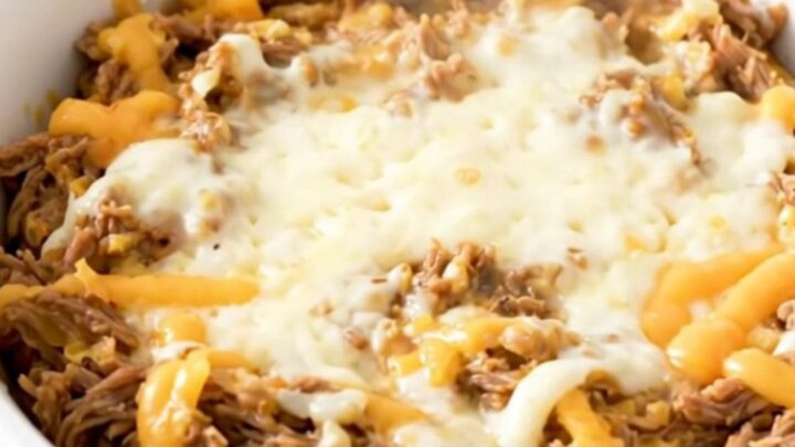 A creamy Philly cheesesteak dip in a white bowl with melted cheese and beef.