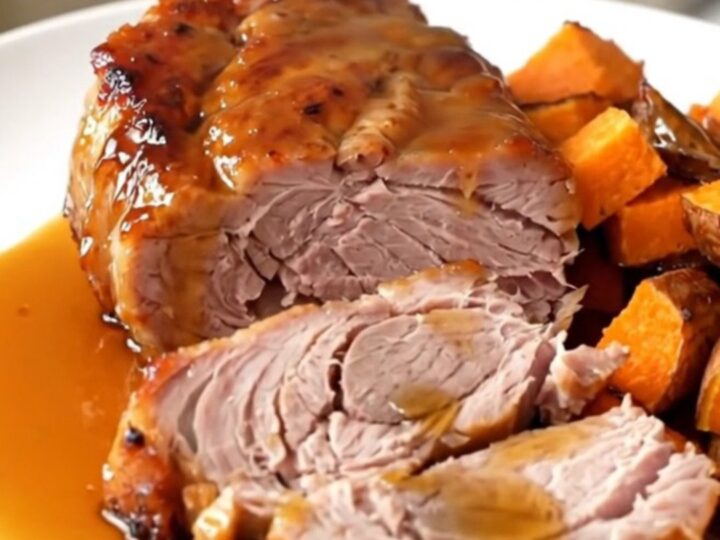 A close-up of glazed pork tenderloin and sweet potatoes served on a white plate.