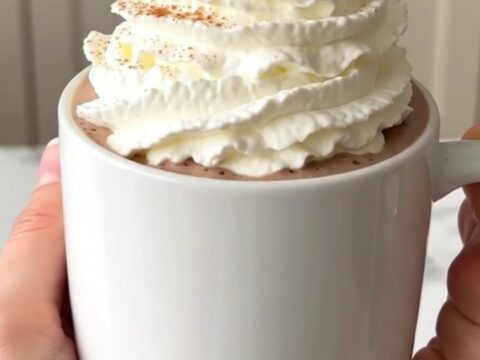 A steaming mug of pumpkin white hot chocolate topped with whipped cream.
