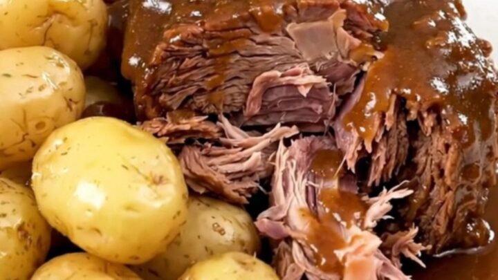 A succulent beef chuck roast served with tender gold potatoes in a slow cooker, looking warm and inviting.