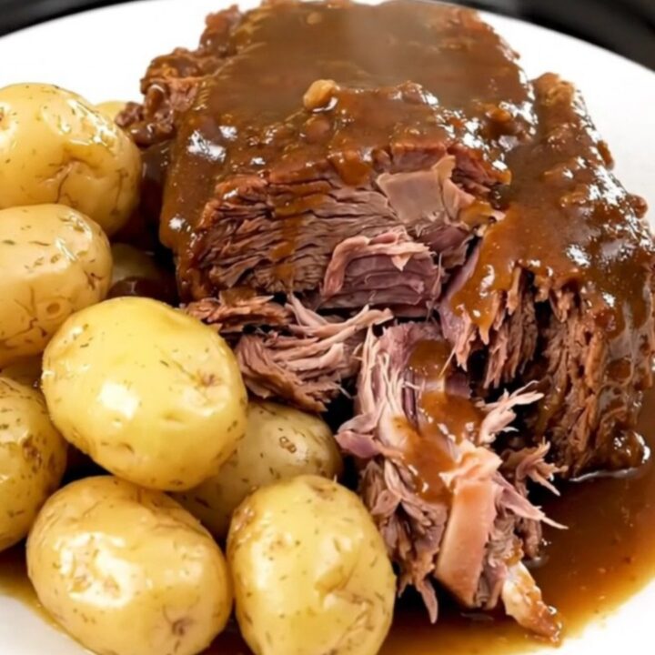 A succulent beef chuck roast served with tender gold potatoes in a slow cooker, looking warm and inviting.
