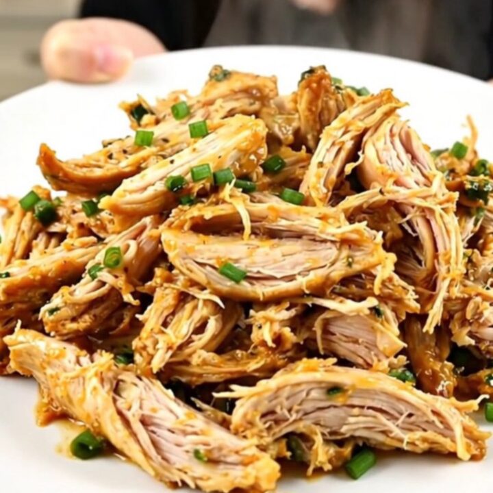 A plate of creamy, shredded Mexican street corn chicken showing tender meat and corn kernels.