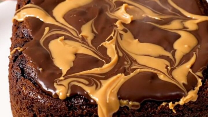 A close-up of a warm, gooey chocolate and peanut butter dump cake served in a white bowl.