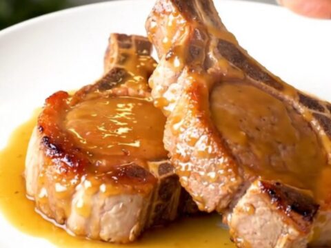 Close-up of tender glazed pork chops on a white plate with a glossy brown sugar and Dijon sauce.