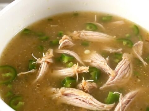 A steaming bowl of creamy jalapeno popper chicken soup garnished with fresh diced jalapenos.