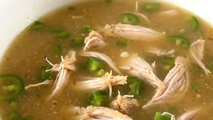 A steaming bowl of creamy jalapeno popper chicken soup garnished with fresh diced jalapenos.