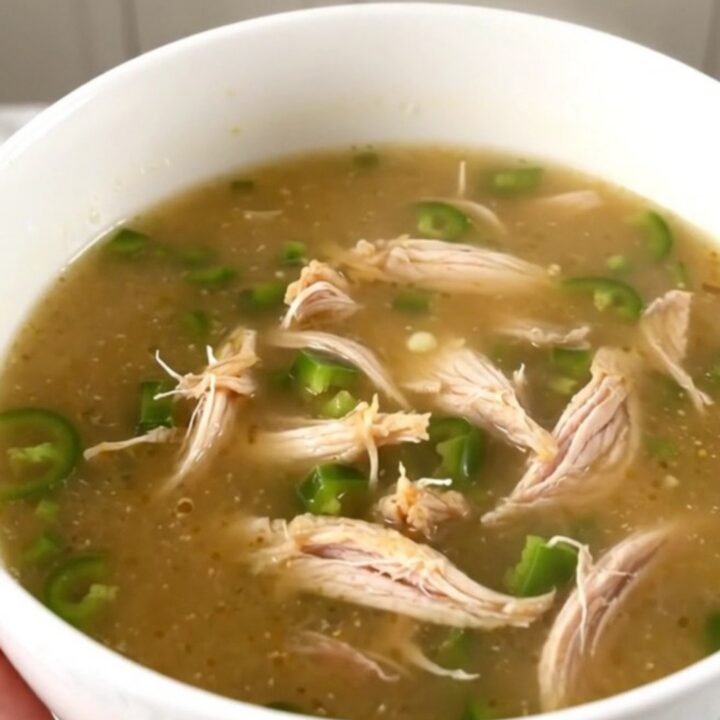 A steaming bowl of creamy jalapeno popper chicken soup garnished with fresh diced jalapenos.