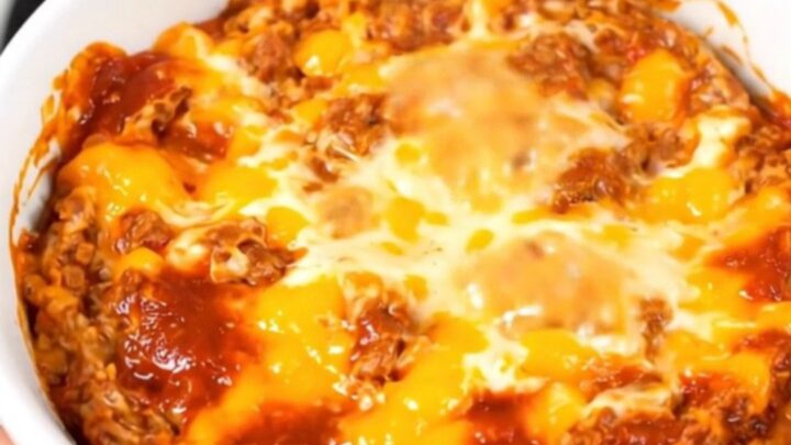 A top-down view of a steaming, creamy chorizo dip in a black slow cooker on a white quartz countertop.