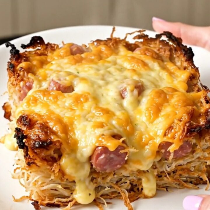 A close-up of a cheesy smoked sausage and hash brown casserole in a slow cooker.
