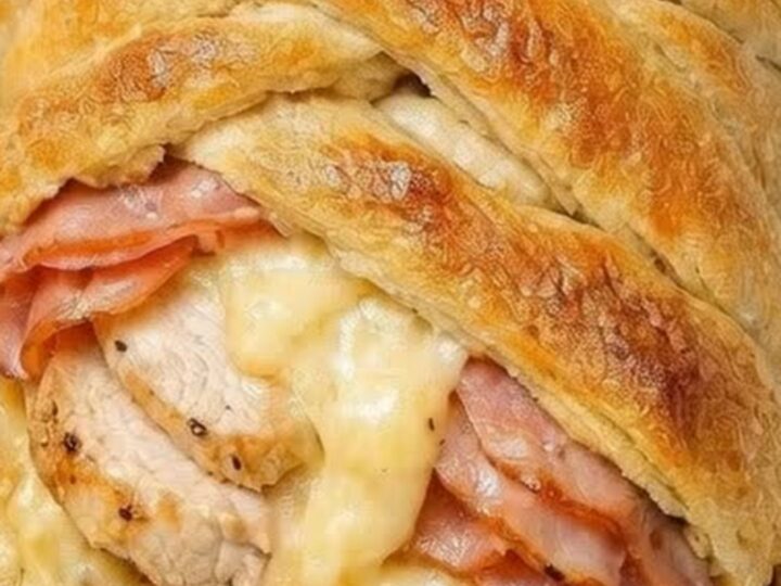 A golden-brown, braided crescent pastry filled with melted Swiss cheese, savory ham, and tender chicken.