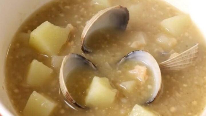 A steaming bowl of creamy New England Clam Chowder with visible potato chunks and clams.