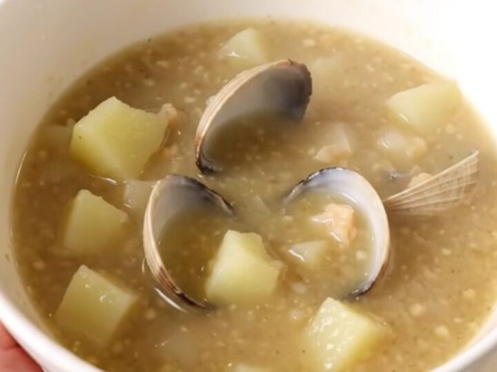 A steaming bowl of creamy New England Clam Chowder with visible potato chunks and clams.