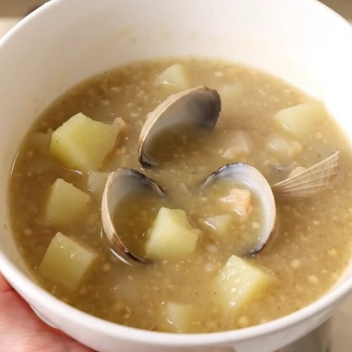 A steaming bowl of creamy New England Clam Chowder with visible potato chunks and clams.