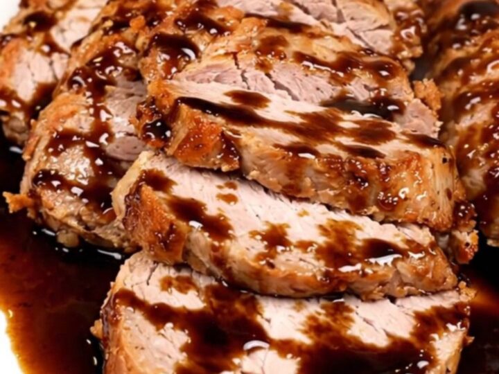 A top-down view of a slow cooker filled with raw pork tenderloin, red onions, and balsamic vinegar.