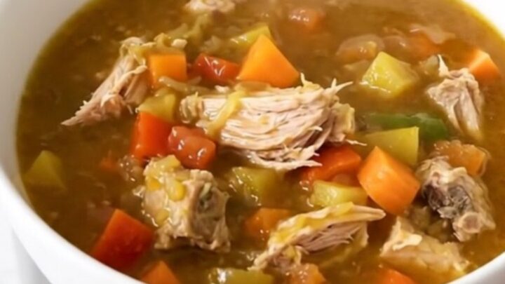 A top-down view of a black slow cooker filled with turkey, sweet potatoes, carrots, and broth.