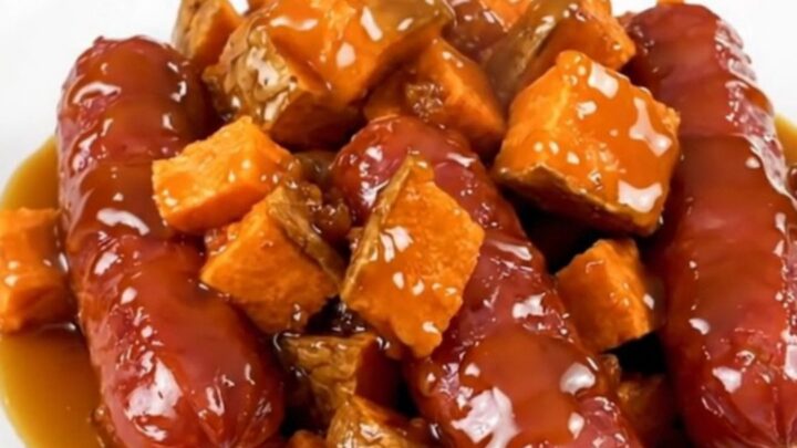 A slow cooker filled with sliced kielbasa and cubed sweet potatoes glazed in a maple butter sauce.