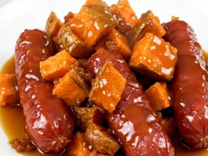A slow cooker filled with sliced kielbasa and cubed sweet potatoes glazed in a maple butter sauce.
