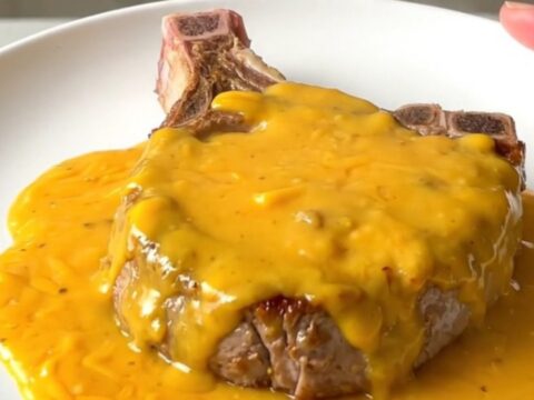 A top-down view of tender pork chops covered in a creamy cheddar and bacon sauce inside a black slow cooker.