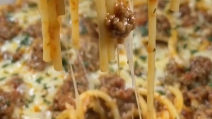 A steaming plate of Cajun beef spaghetti with garlic cheddar cream sauce showing an epic cheese pull.