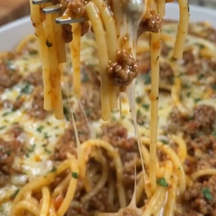 A steaming plate of Cajun beef spaghetti with garlic cheddar cream sauce showing an epic cheese pull.