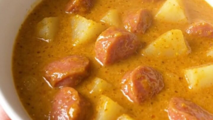 A steaming bowl of creamy bratwurst chowder with visible potato chunks and sausage rounds.