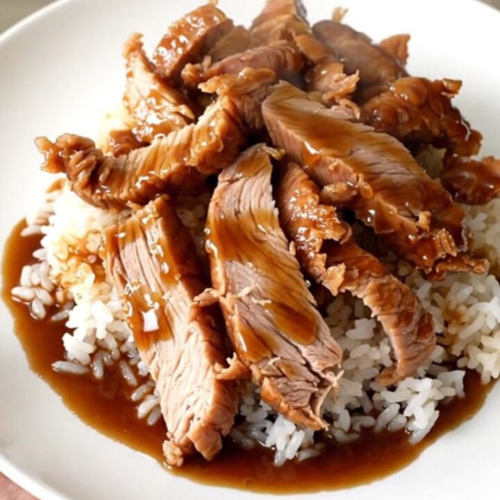 Slow cooker filled with raw pork tenderloin, bell peppers, and teriyaki sauce ready for cooking.