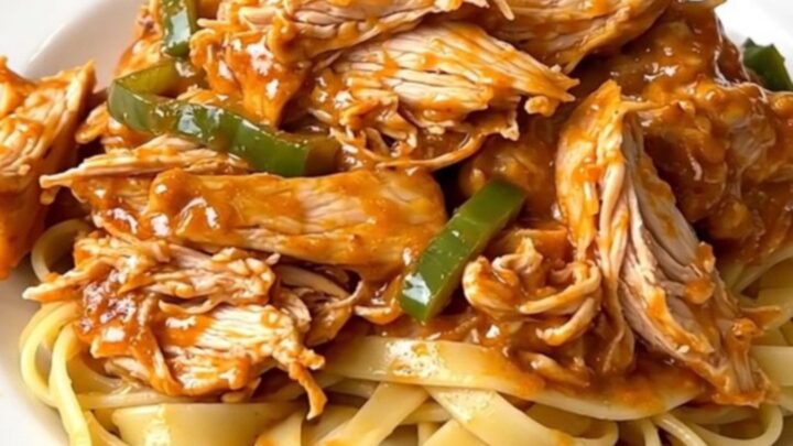 Creamy Cajun chicken alfredo served on a white plate with steaming fettuccine noodles.