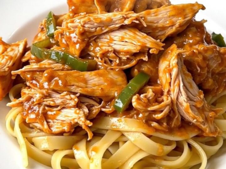 Creamy Cajun chicken alfredo served on a white plate with steaming fettuccine noodles.
