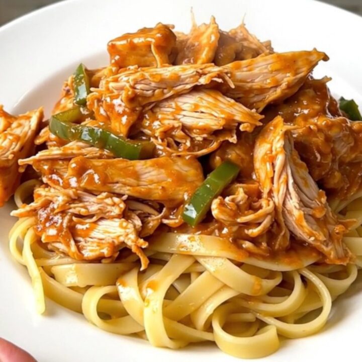 Creamy Cajun chicken alfredo served on a white plate with steaming fettuccine noodles.