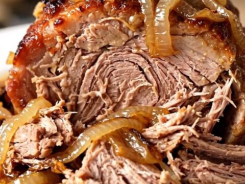 A slow cooker filled with a tender pork roast and caramelized onions.