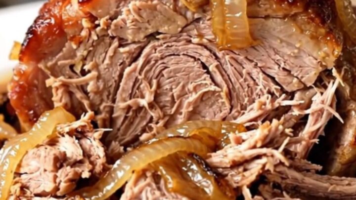 A slow cooker filled with a tender pork roast and caramelized onions.
