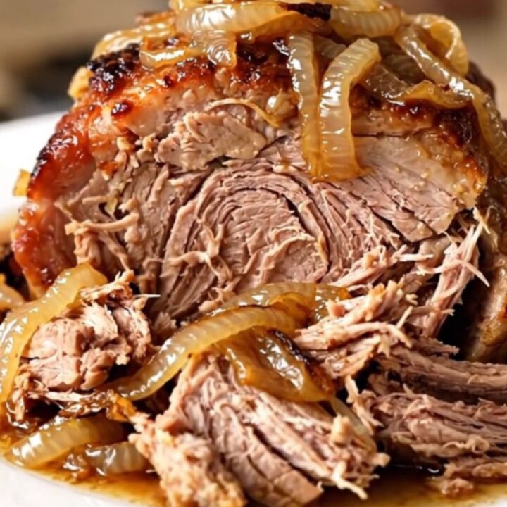 A slow cooker filled with a tender pork roast and caramelized onions.