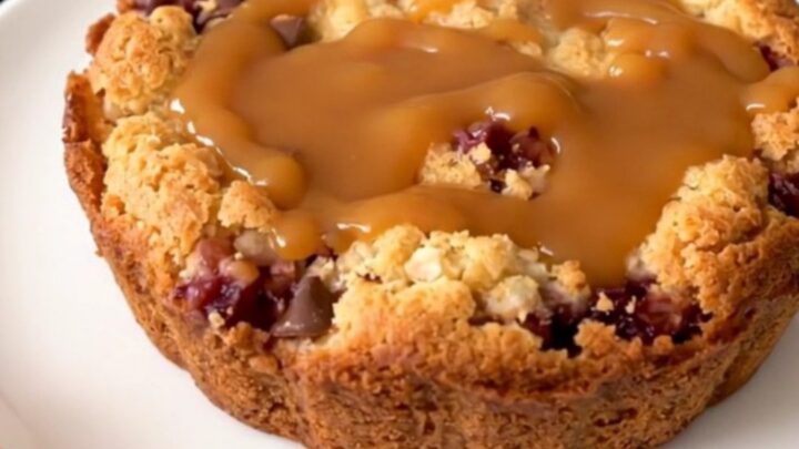 A warm, golden brown apple cobbler topped with crunchy toffee bits and drizzled with rich caramel sauce.